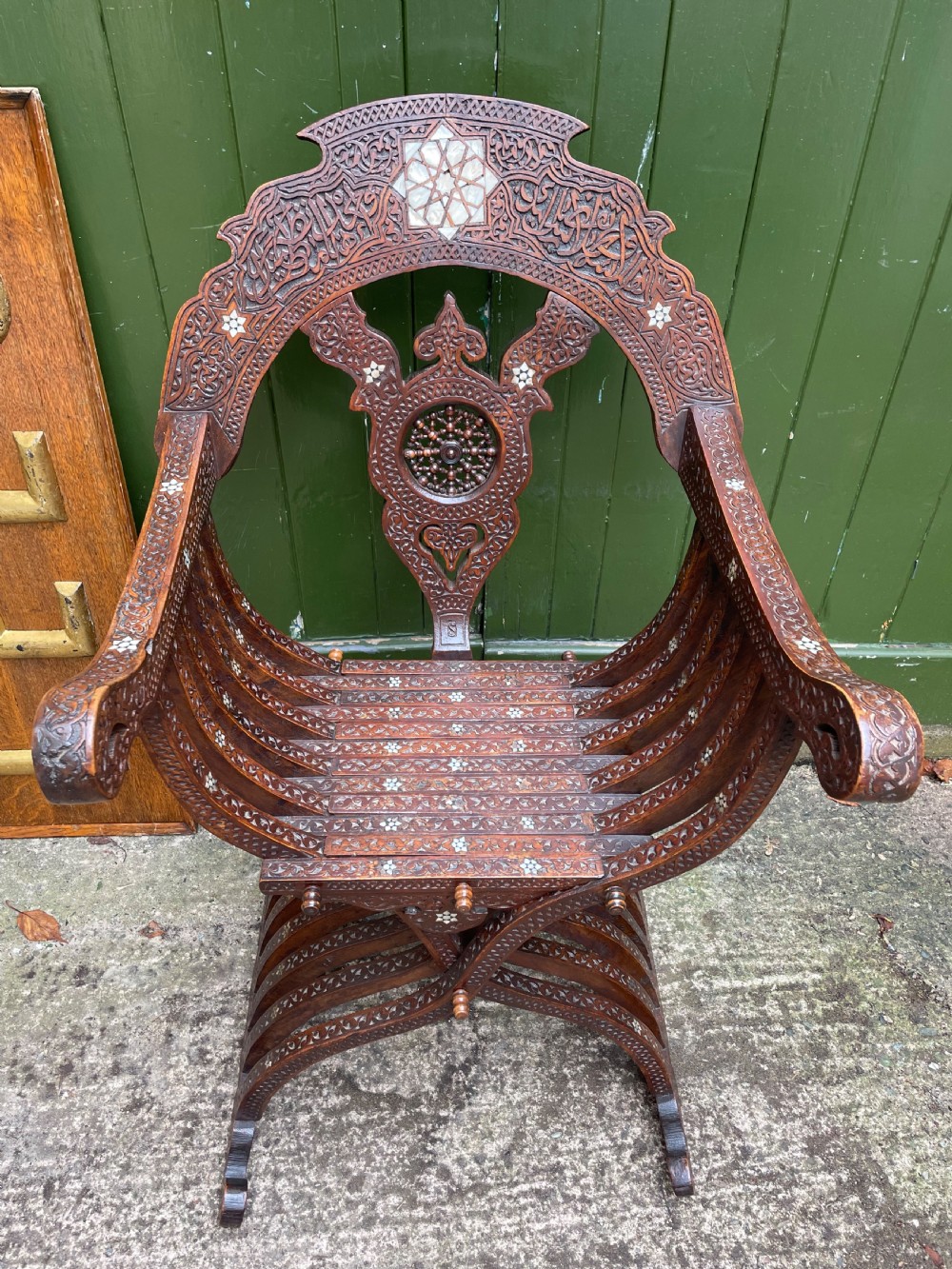 A Syrian dark walnut X-frame armchair featuring intricate Arabic calligraphy carvings and geometric mother-of-pearl shell inlay throughout. View VII