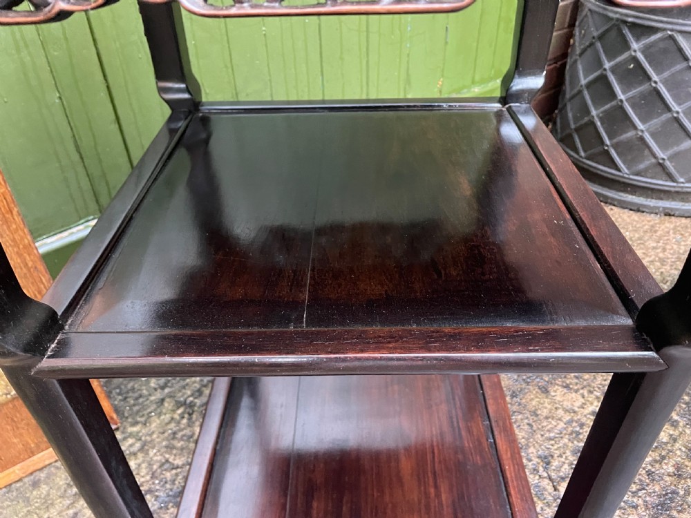 A late nineteenth-century Chinese square dark hardwood two-tier side table featuring intricately carved floral openwork aprons and lower shelf tiers. View X