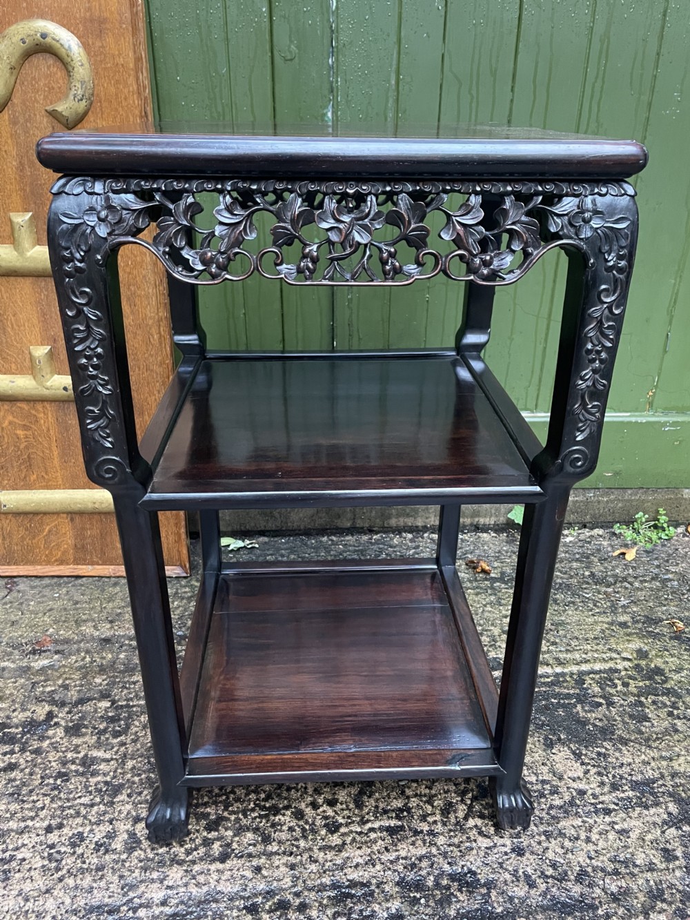 A late nineteenth-century Chinese square dark hardwood two-tier side table featuring intricately carved floral openwork aprons and lower shelf tiers.