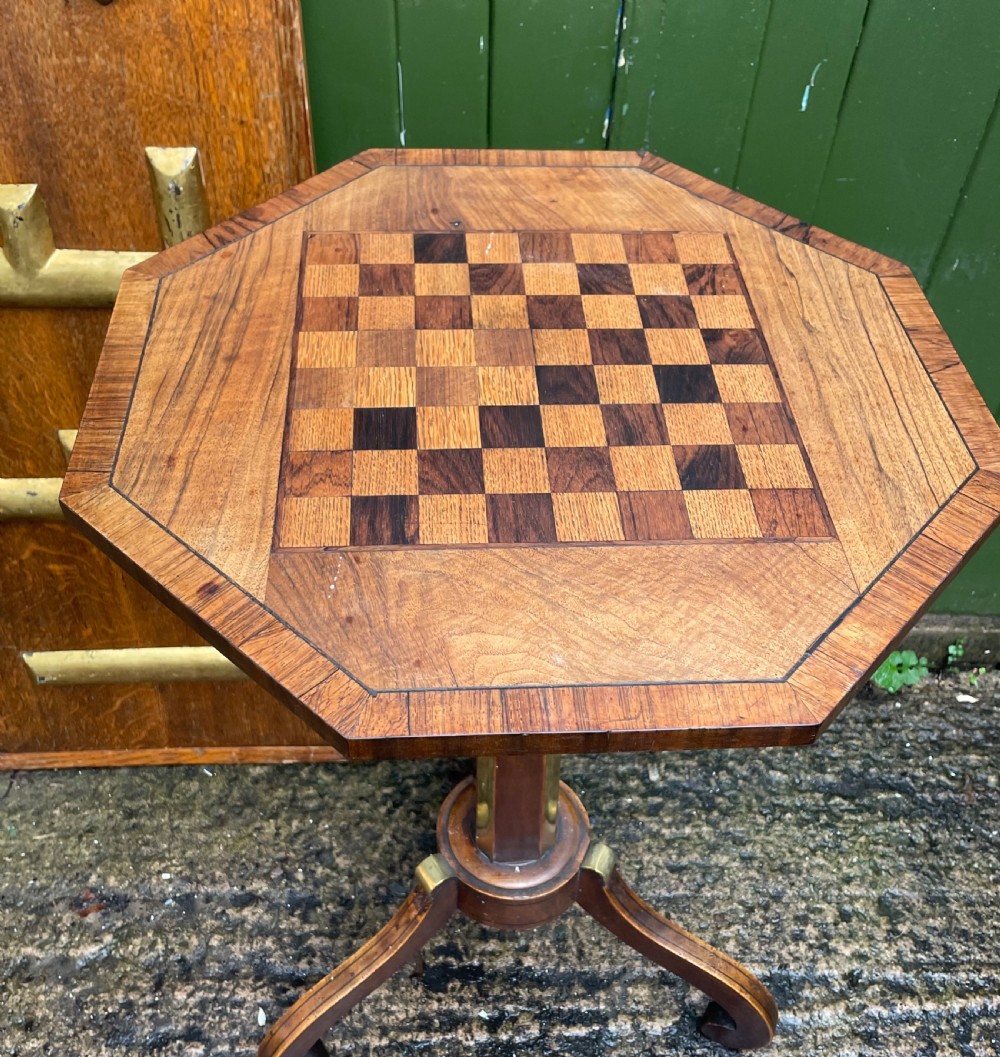 An early nineteenth-century Regency octagonal rosewood games table with a chequerboard inlaid top, brass mounts, and a tripod base. View III