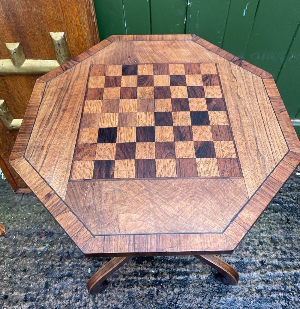 An early nineteenth-century Regency octagonal rosewood games table with a chequerboard inlaid top, brass mounts, and a tripod base. View VI