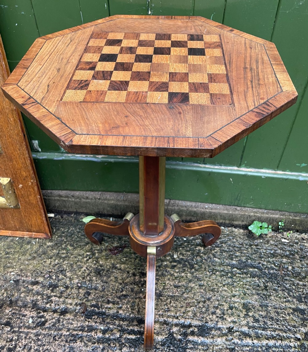 An early nineteenth-century Regency octagonal rosewood games table with a chequerboard inlaid top, brass mounts, and a tripod base. View XI