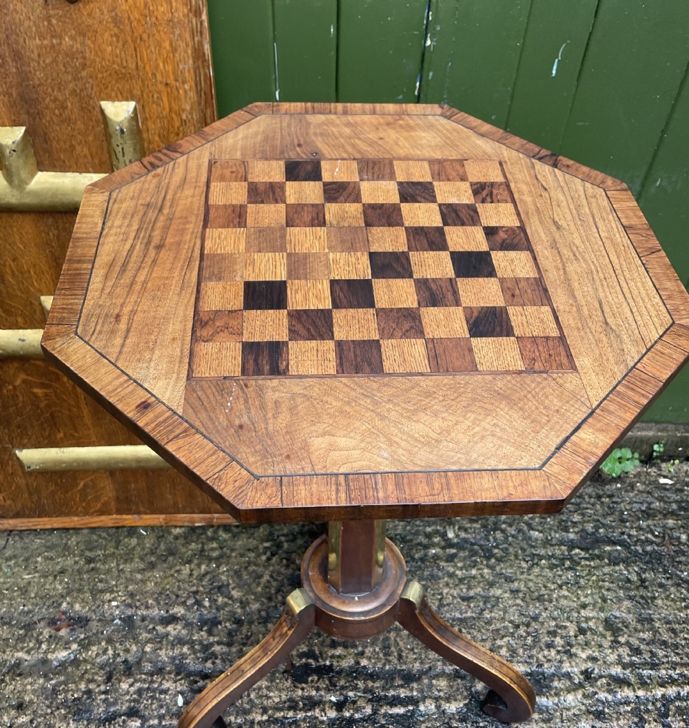 An early nineteenth-century Regency octagonal rosewood games table with a chequerboard inlaid top, brass mounts, and a tripod base. View II