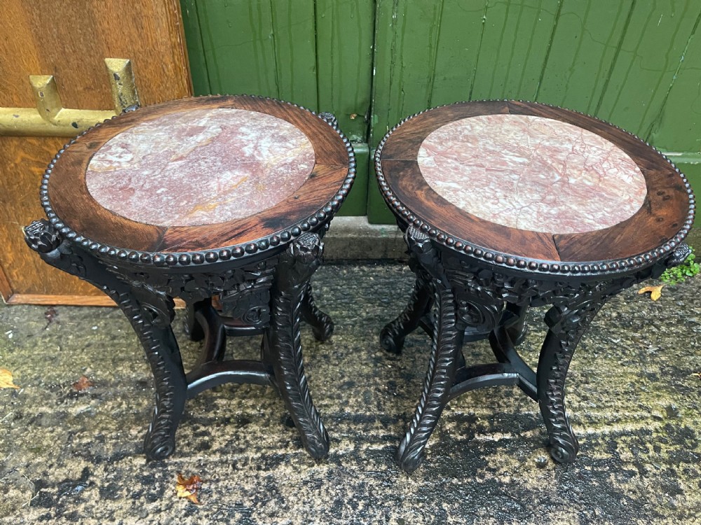 A pair of circular late nineteenth-century Chinese hardwood stands featuring inset pinkish rouge marble tops and intricately carved aprons and legs. View II