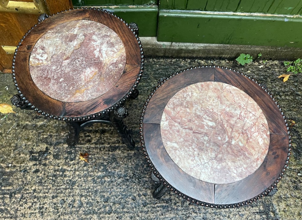 A pair of circular late nineteenth-century Chinese hardwood stands featuring inset pinkish rouge marble tops and intricately carved aprons and legs. View V