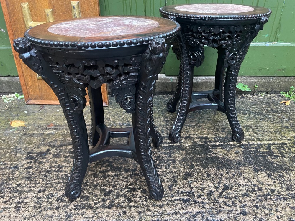 A pair of circular late nineteenth-century Chinese hardwood stands featuring inset pinkish rouge marble tops and intricately carved aprons and legs. View IX