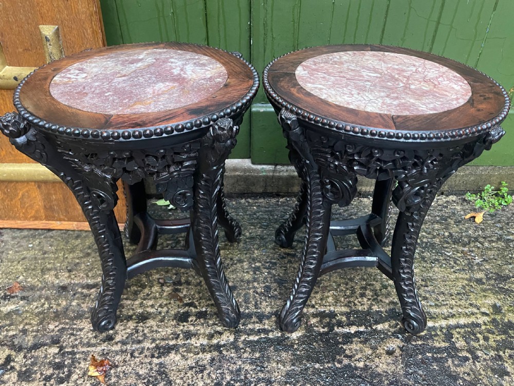 A pair of circular late nineteenth-century Chinese hardwood stands featuring inset pinkish rouge marble tops and intricately carved aprons and legs. View X
