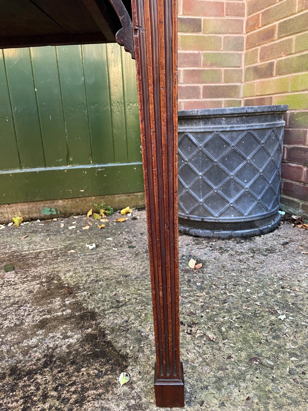 A late 18th-century George III mahogany pier table featuring fluted legs, carved corner brackets, and a rectangular polished top. View VI