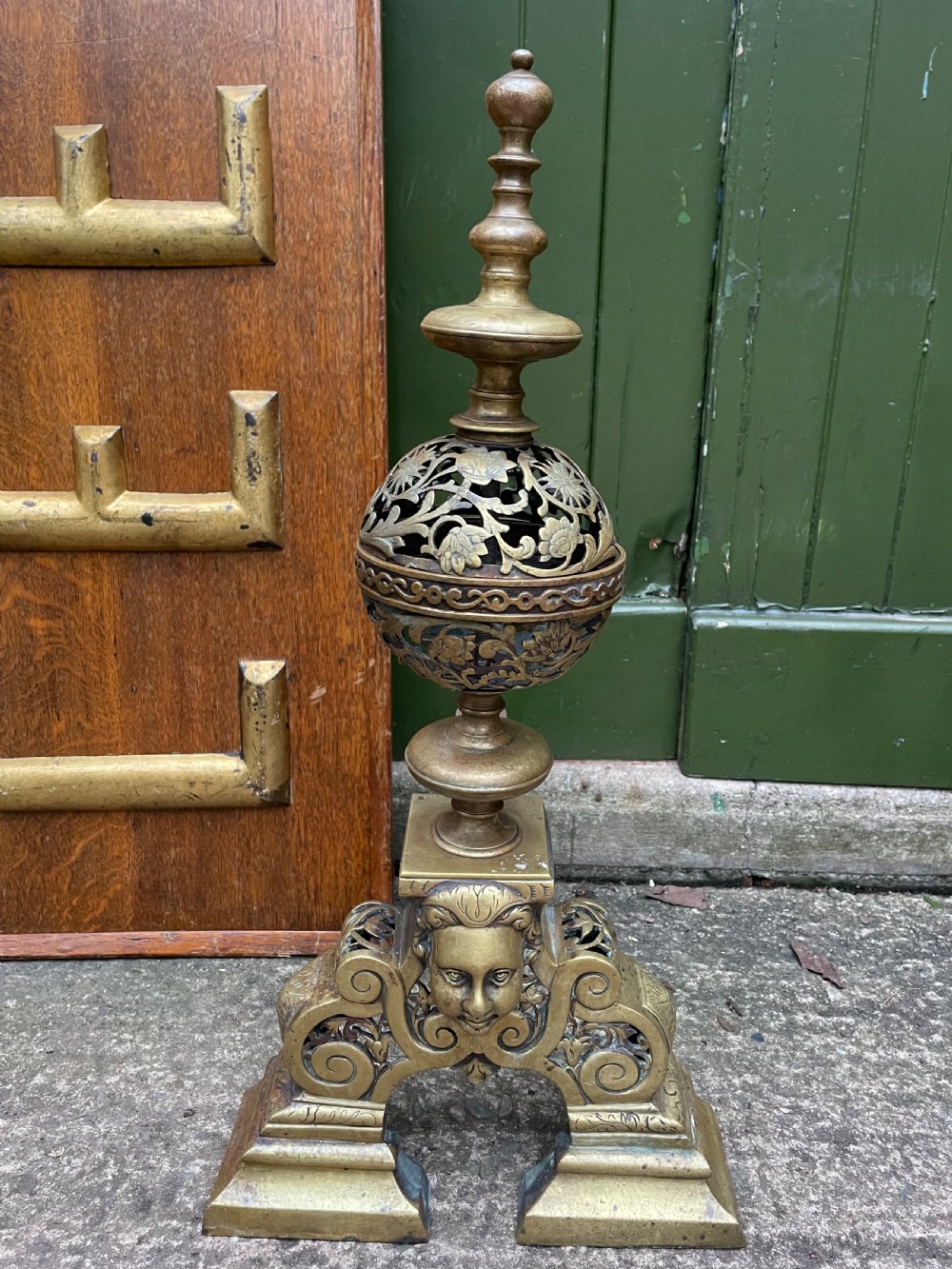 A pair of 19th-century Baroque revival brass andirons featuring mascaron face motifs, openwork spherical finials, and scrolled bases. View III