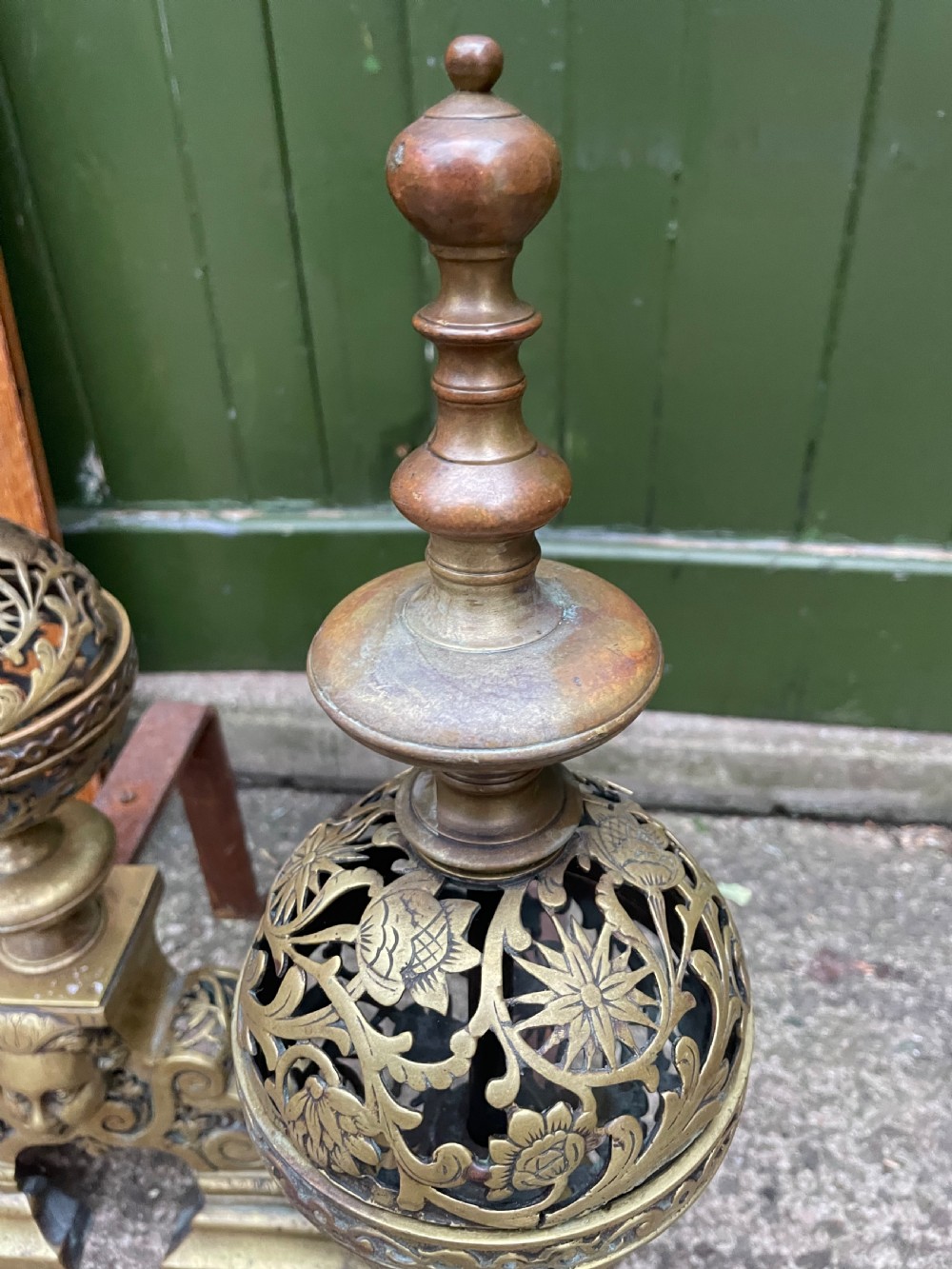 A pair of 19th-century Baroque revival brass andirons featuring mascaron face motifs, openwork spherical finials, and scrolled bases. View VIII