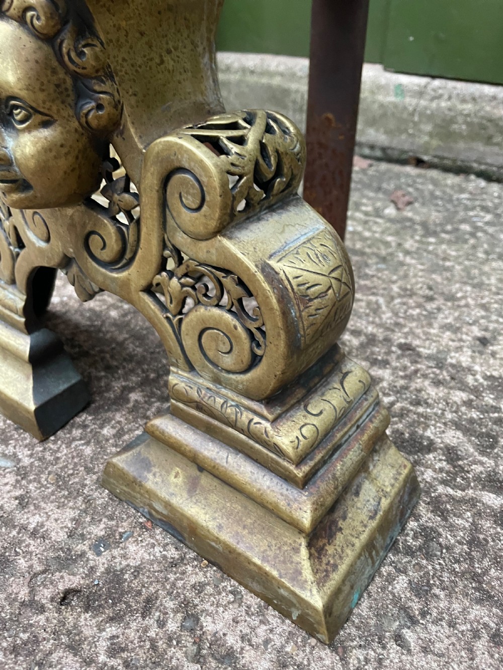 A pair of 19th-century Baroque revival brass andirons featuring mascaron face motifs, openwork spherical finials, and scrolled bases. View X