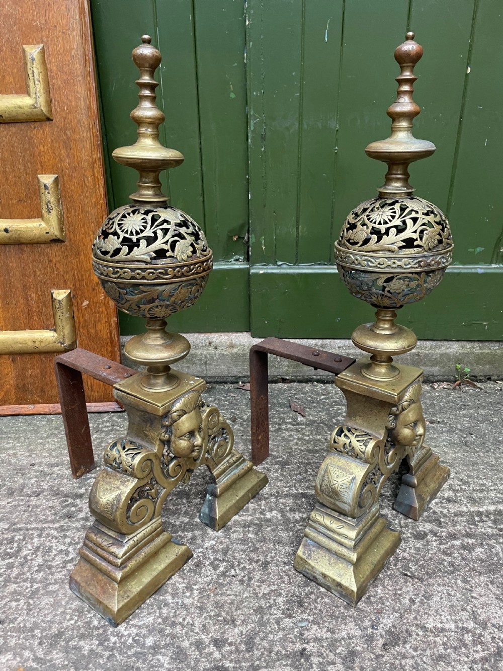 A pair of 19th-century Baroque revival brass andirons featuring mascaron face motifs, openwork spherical finials, and scrolled bases. View XI