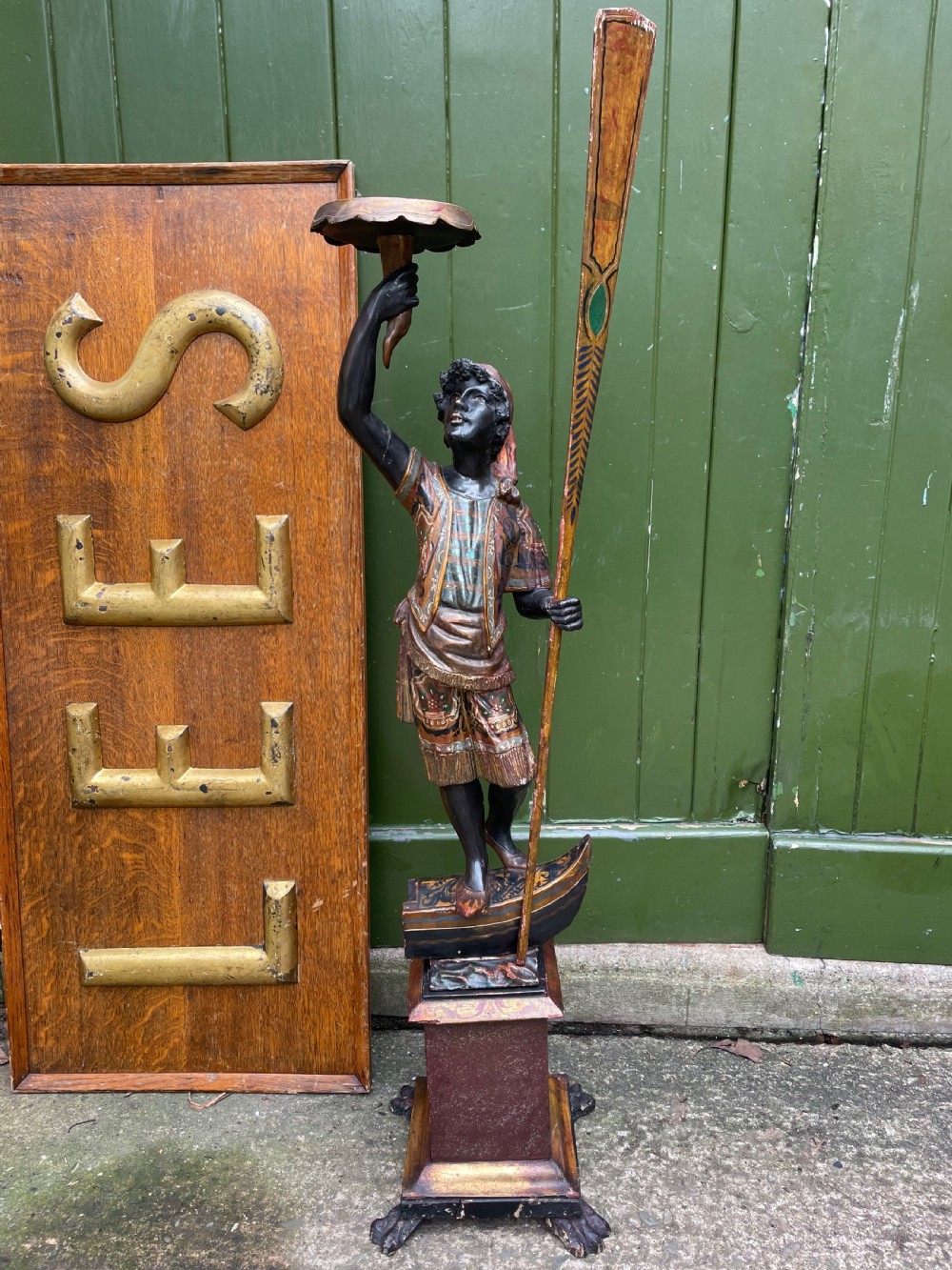 A late 19th-century Italian Venetian carved wood polychrome figure of a gondolier standing on a boat base atop a plinth, holding an oar and raised tray. View II