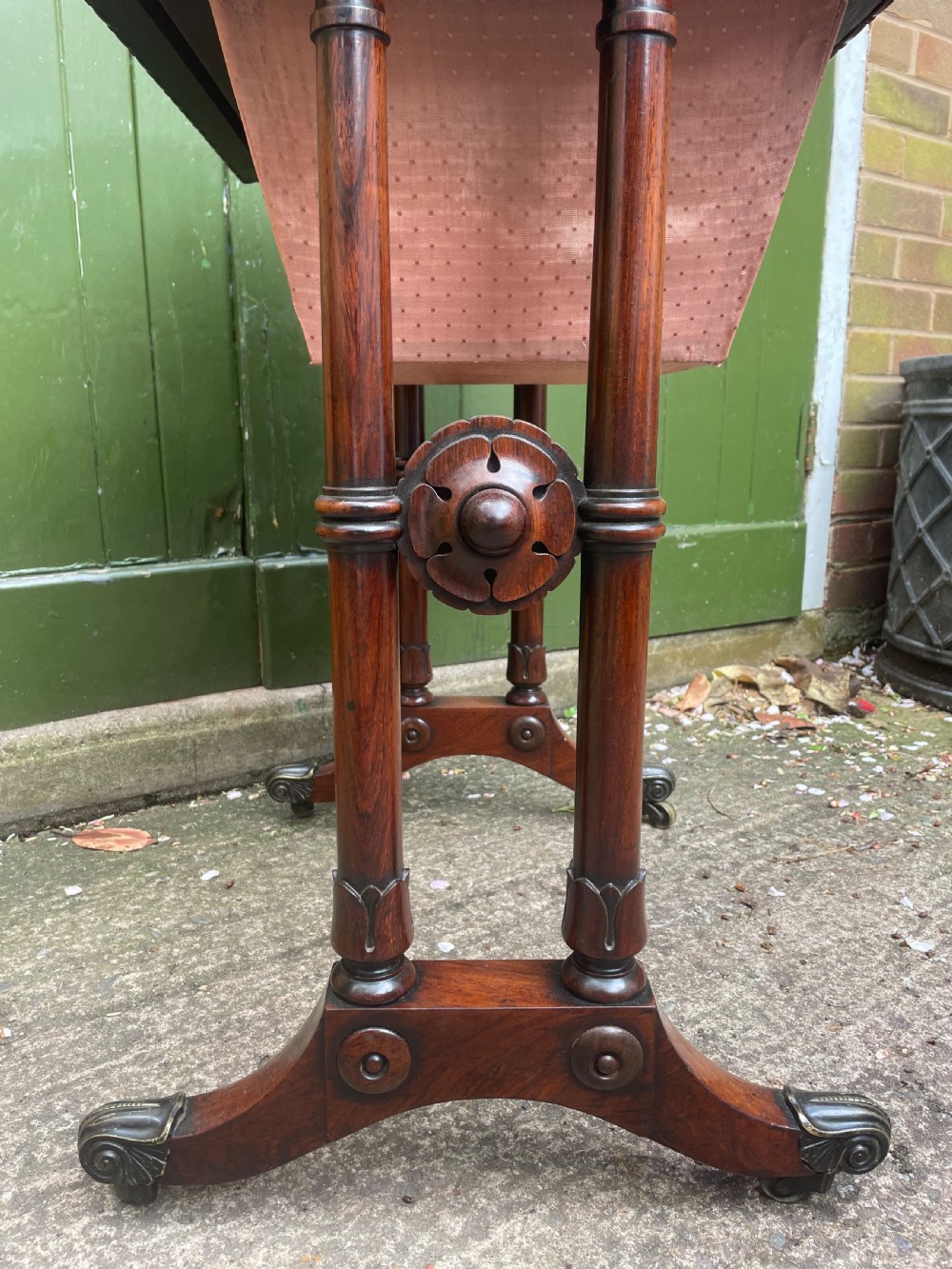 An early 19th-century George IV figured rosewood work table featuring a smooth polished top, single drawer, fabric work basket, turned twin-column supports, and brass castors. View XXII