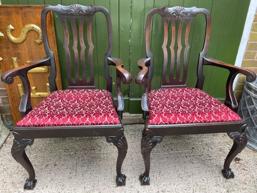 A pair of 19th-century mahogany open armchairs featuring carved shell cresting, pierced vertical splats, patterned red velvet seats, and cabriole legs with claw and ball feet. View II