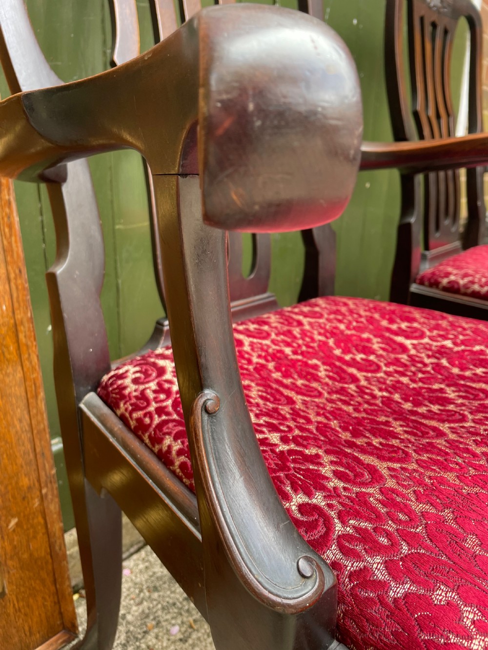 A pair of 19th-century mahogany open armchairs featuring carved shell cresting, pierced vertical splats, patterned red velvet seats, and cabriole legs with claw and ball feet. View V