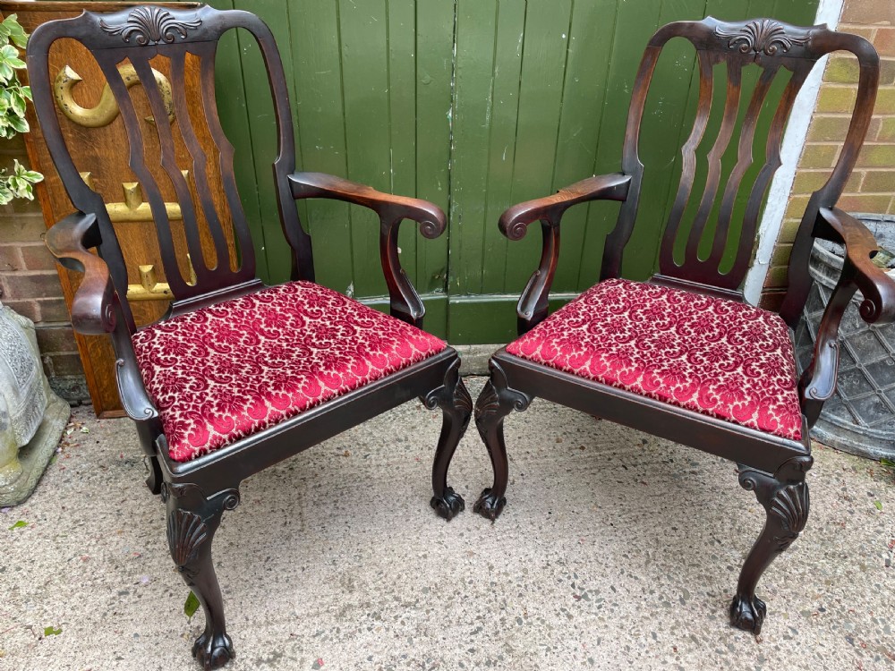 A pair of 19th-century mahogany open armchairs featuring carved shell cresting, pierced vertical splats, patterned red velvet seats, and cabriole legs with claw and ball feet. View IX