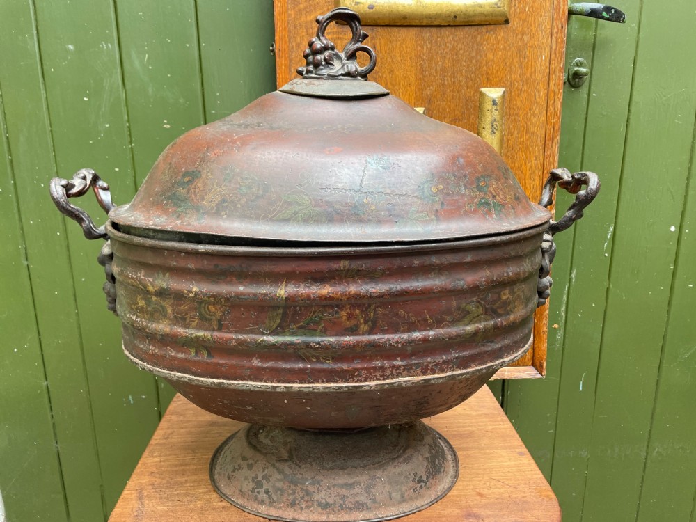 An early nineteenth-century round japanned tinware wine cooler with a domed lid, pedestal base, twin loop handles, and faded painted floral motifs. View IV