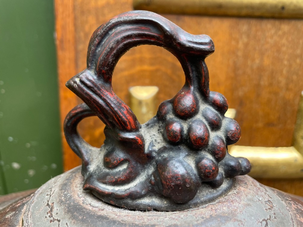 An early nineteenth-century round japanned tinware wine cooler with a domed lid, pedestal base, twin loop handles, and faded painted floral motifs. View V