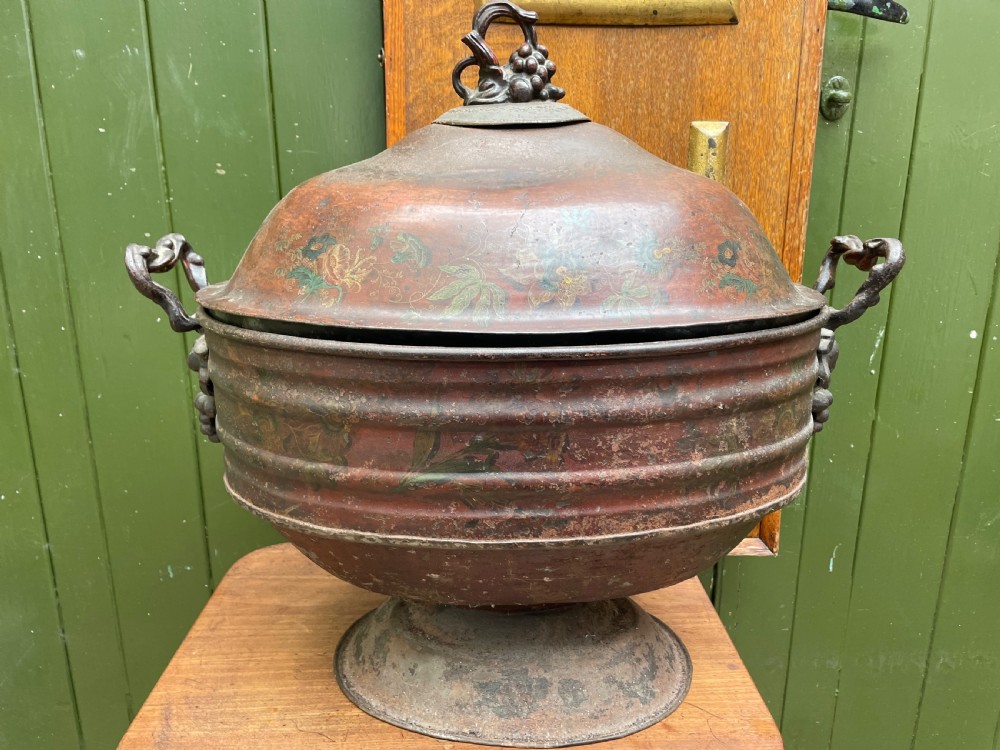 An early nineteenth-century round japanned tinware wine cooler with a domed lid, pedestal base, twin loop handles, and faded painted floral motifs. View VII