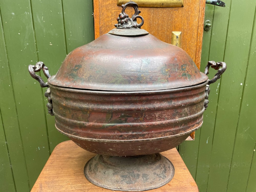 An early nineteenth-century round japanned tinware wine cooler with a domed lid, pedestal base, twin loop handles, and faded painted floral motifs. View IX