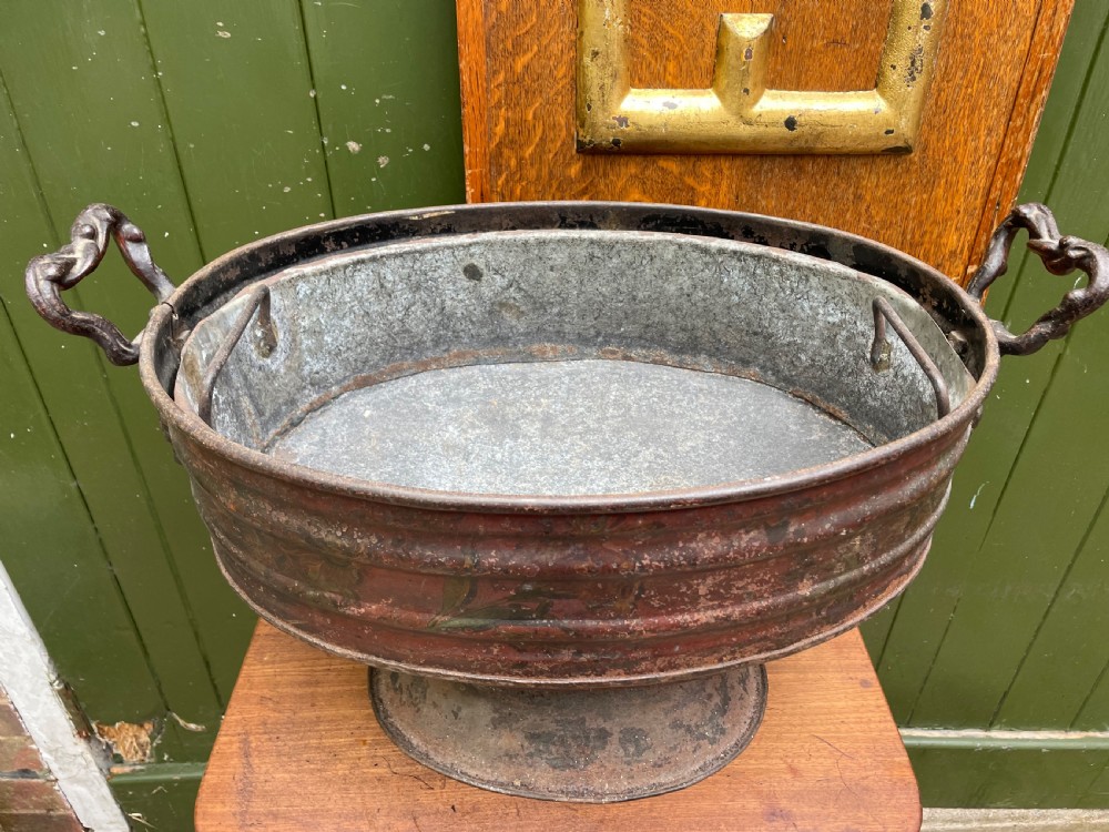 An early nineteenth-century round japanned tinware wine cooler with a domed lid, pedestal base, twin loop handles, and faded painted floral motifs. View XII