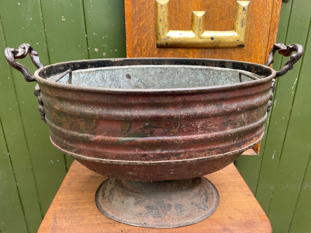 An early nineteenth-century round japanned tinware wine cooler with a domed lid, pedestal base, twin loop handles, and faded painted floral motifs. View XVIII