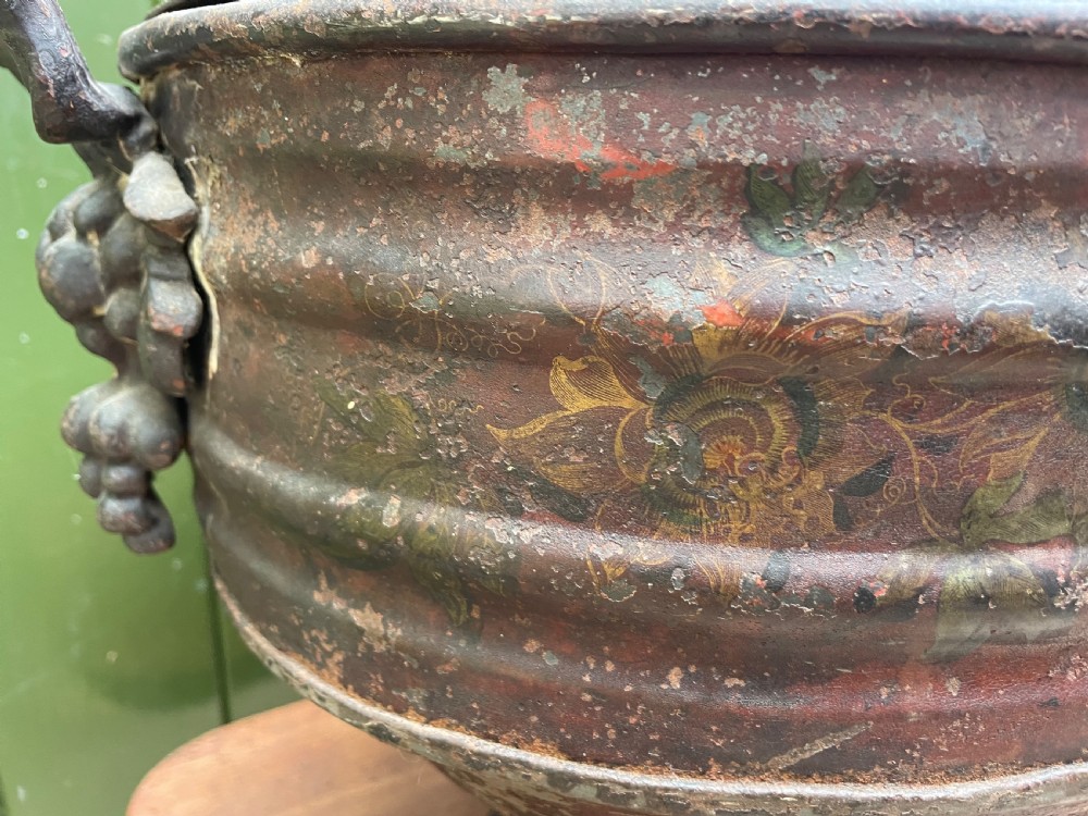 An early nineteenth-century round japanned tinware wine cooler with a domed lid, pedestal base, twin loop handles, and faded painted floral motifs. View XXII