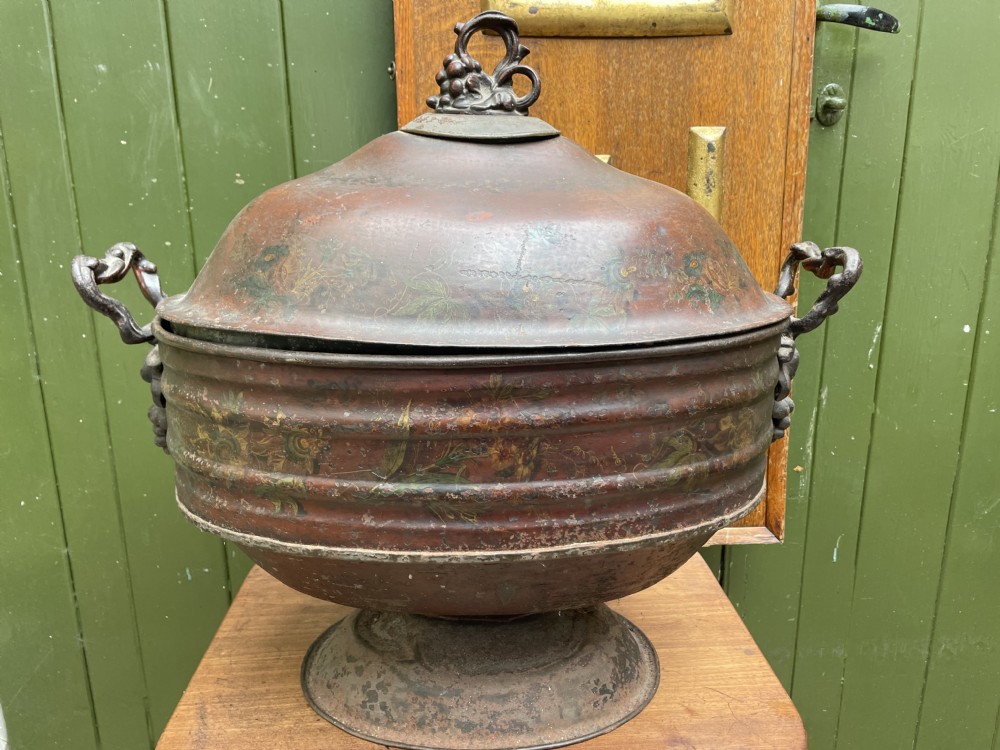 An early nineteenth-century round japanned tinware wine cooler with a domed lid, pedestal base, twin loop handles, and faded painted floral motifs. View XXV