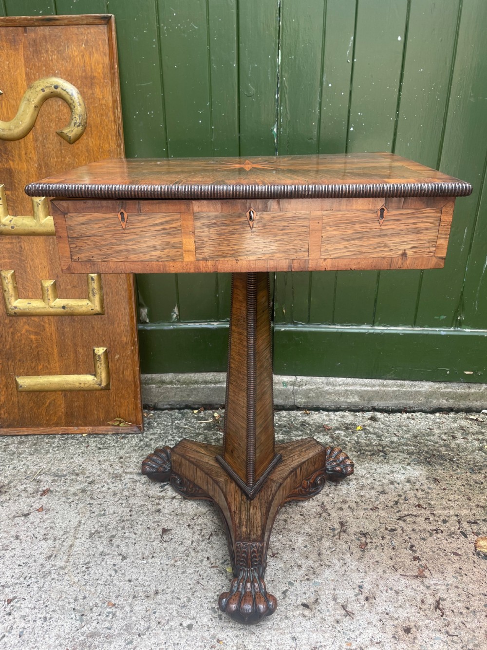 An early nineteenth-century George IV rosewood work table featuring a star-inlaid top, a single drawer casing, a tapered reeded column, and a tripartite base supported by carved claw feet.