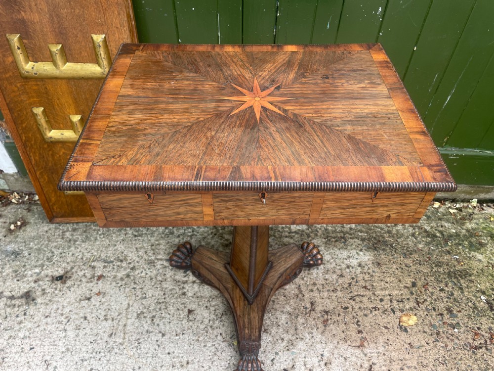 An early nineteenth-century George IV rosewood work table featuring a star-inlaid top, a single drawer casing, a tapered reeded column, and a tripartite base supported by carved claw feet. View II