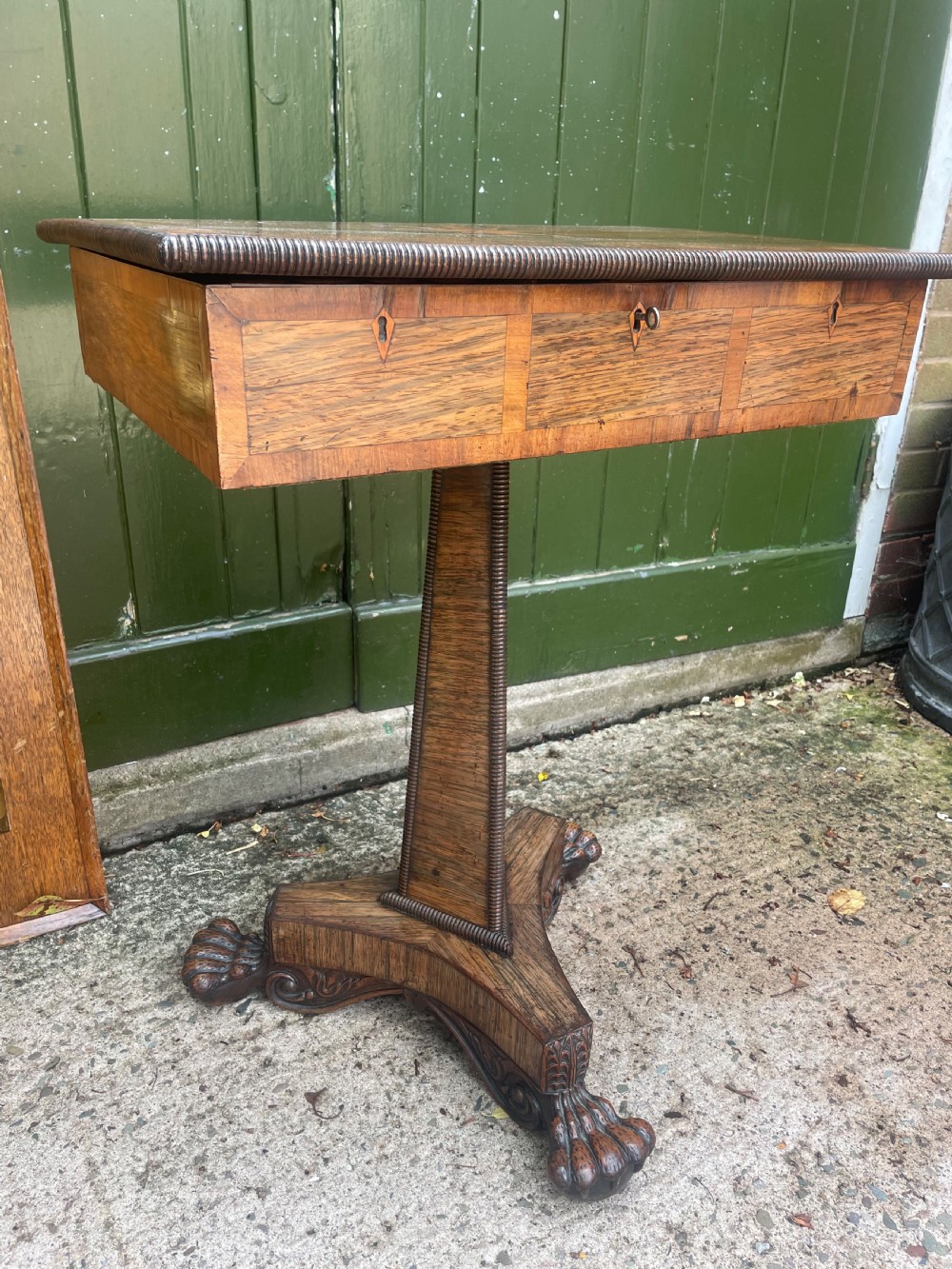An early nineteenth-century George IV rosewood work table featuring a star-inlaid top, a single drawer casing, a tapered reeded column, and a tripartite base supported by carved claw feet. View III