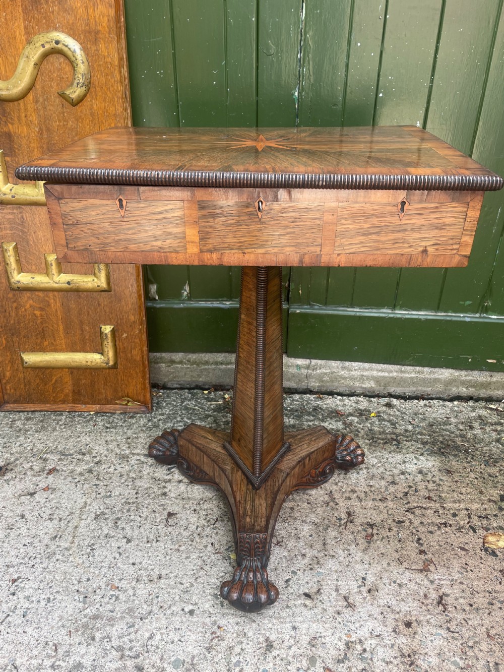 An early nineteenth-century George IV rosewood work table featuring a star-inlaid top, a single drawer casing, a tapered reeded column, and a tripartite base supported by carved claw feet. View VII