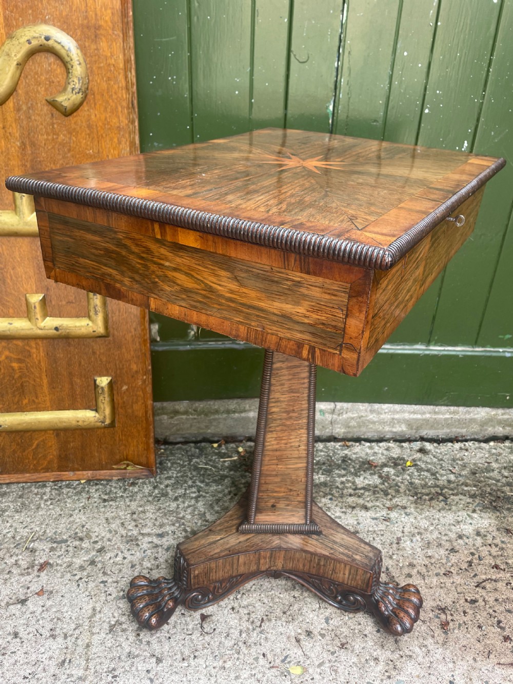 An early nineteenth-century George IV rosewood work table featuring a star-inlaid top, a single drawer casing, a tapered reeded column, and a tripartite base supported by carved claw feet. View XI