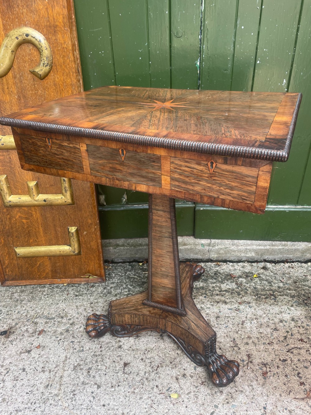 An early nineteenth-century George IV rosewood work table featuring a star-inlaid top, a single drawer casing, a tapered reeded column, and a tripartite base supported by carved claw feet. View XII