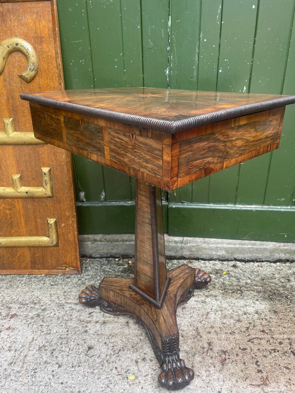 An early nineteenth-century George IV rosewood work table featuring a star-inlaid top, a single drawer casing, a tapered reeded column, and a tripartite base supported by carved claw feet. View XV
