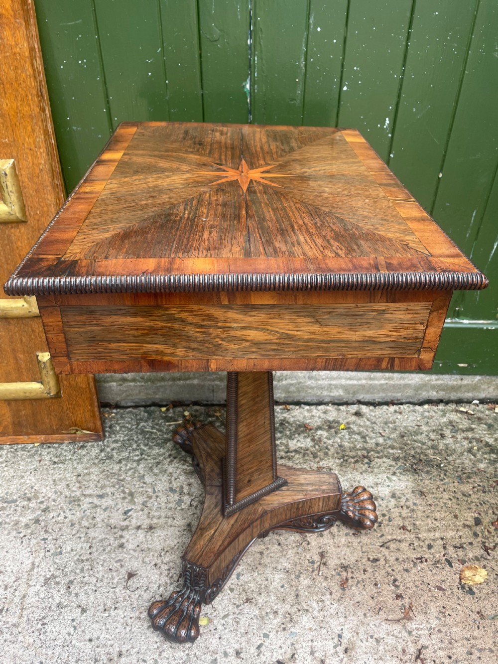 An early nineteenth-century George IV rosewood work table featuring a star-inlaid top, a single drawer casing, a tapered reeded column, and a tripartite base supported by carved claw feet. View XVI
