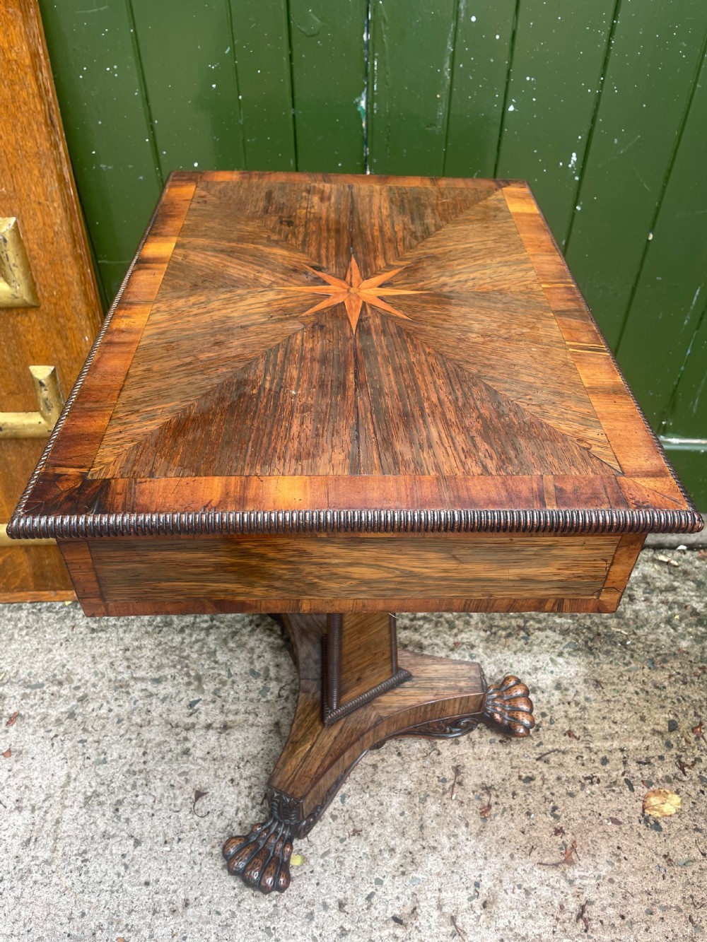 An early nineteenth-century George IV rosewood work table featuring a star-inlaid top, a single drawer casing, a tapered reeded column, and a tripartite base supported by carved claw feet. View XVII