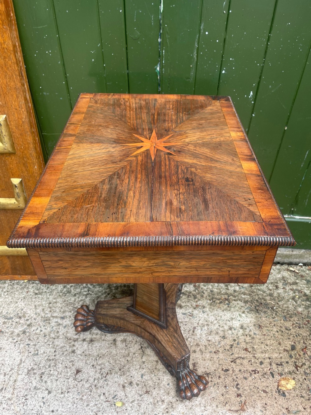 An early nineteenth-century George IV rosewood work table featuring a star-inlaid top, a single drawer casing, a tapered reeded column, and a tripartite base supported by carved claw feet. View XXI