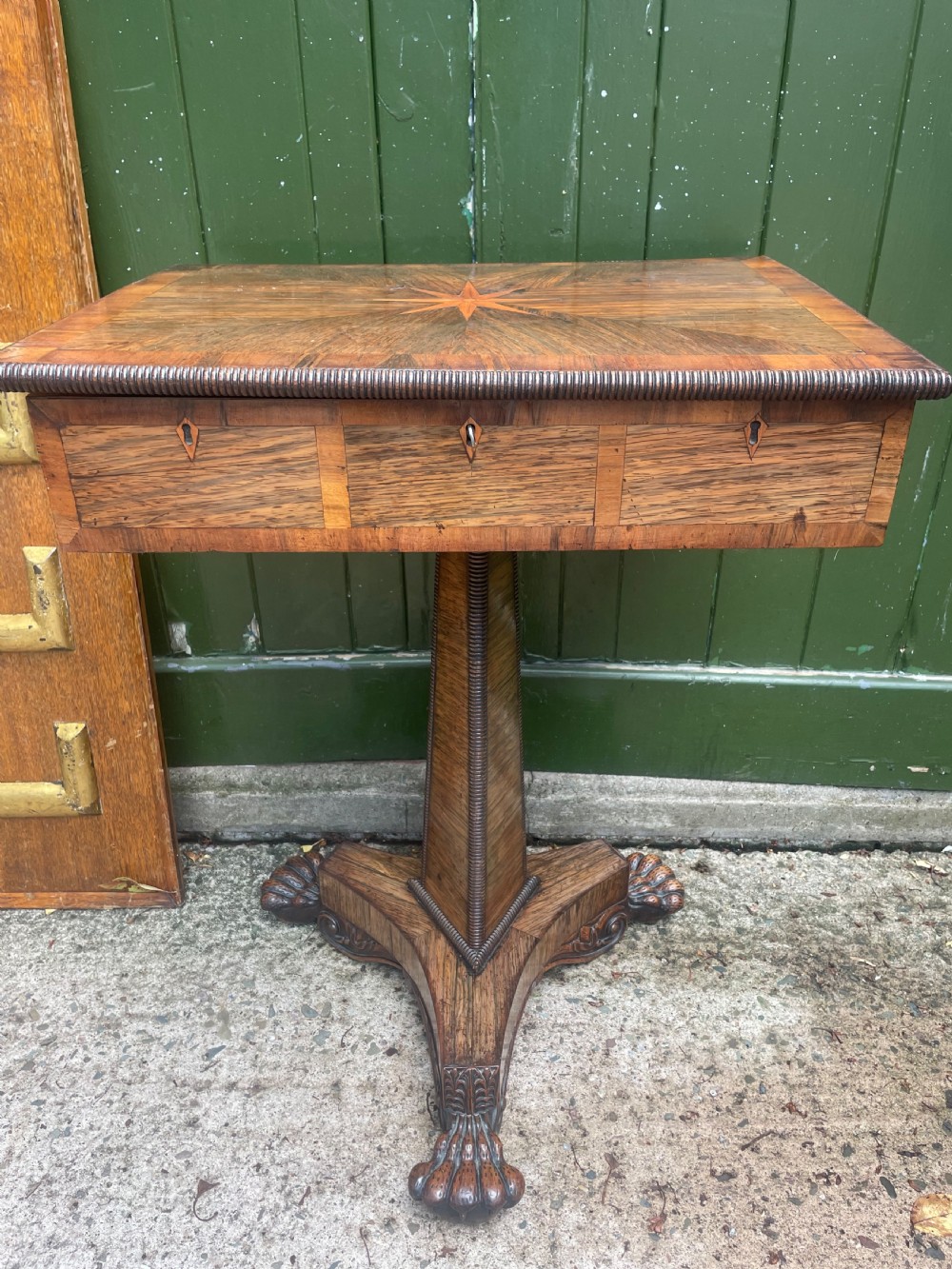 An early nineteenth-century George IV rosewood work table featuring a star-inlaid top, a single drawer casing, a tapered reeded column, and a tripartite base supported by carved claw feet. View XXII