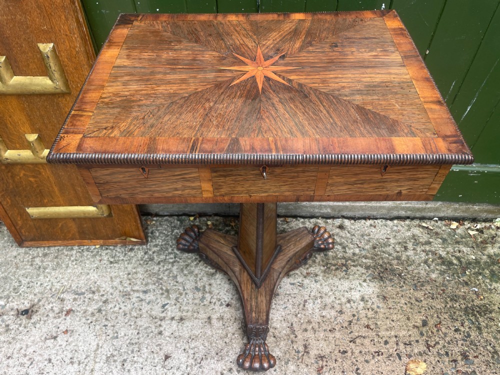 An early nineteenth-century George IV rosewood work table featuring a star-inlaid top, a single drawer casing, a tapered reeded column, and a tripartite base supported by carved claw feet. View XXIII