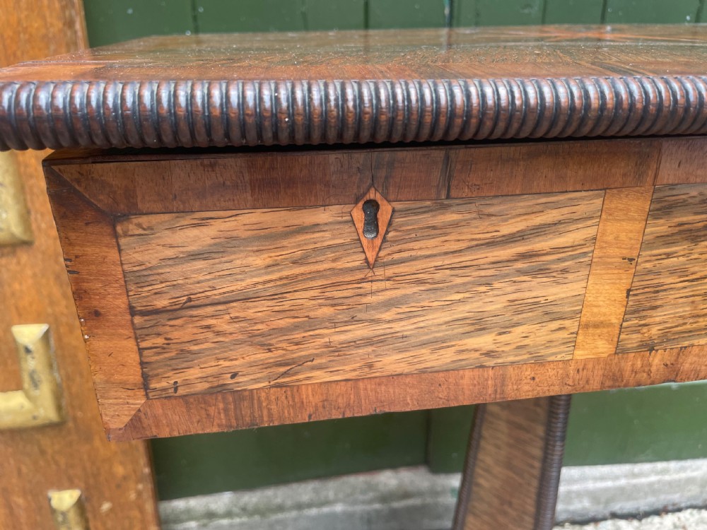 An early nineteenth-century George IV rosewood work table featuring a star-inlaid top, a single drawer casing, a tapered reeded column, and a tripartite base supported by carved claw feet. View XXVI