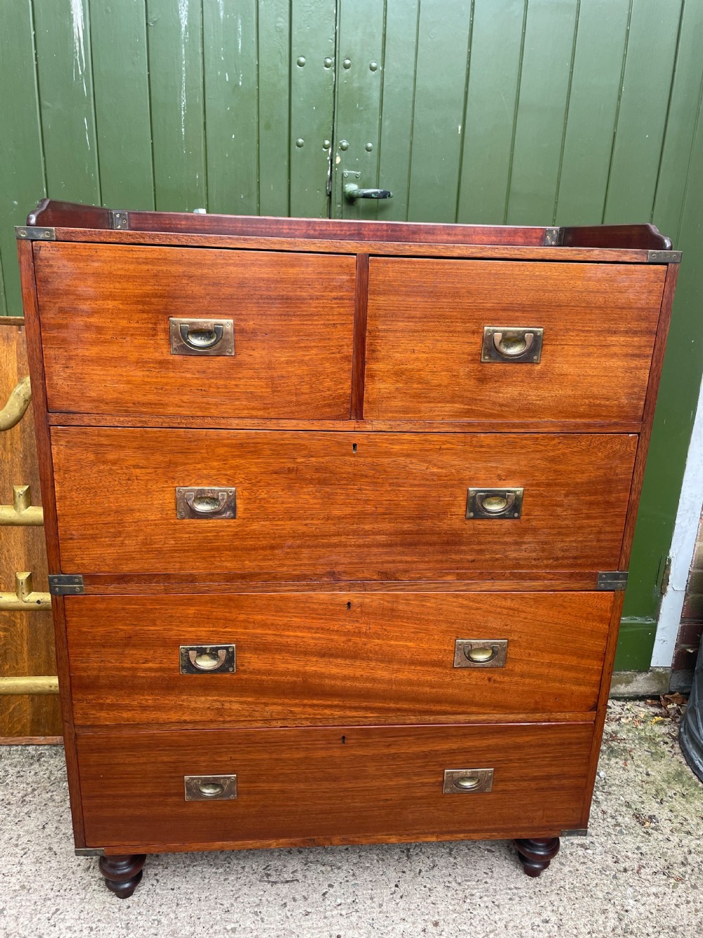 A mid-nineteenth century brass-bound teak campaign chest of drawers featuring two-part construction, recessed brass handles, corner straps, and turned feet. View IX