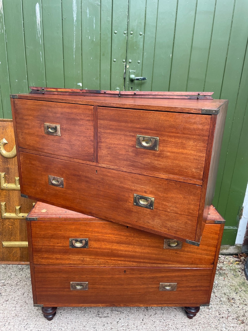 A mid-nineteenth century brass-bound teak campaign chest of drawers featuring two-part construction, recessed brass handles, corner straps, and turned feet. View XI