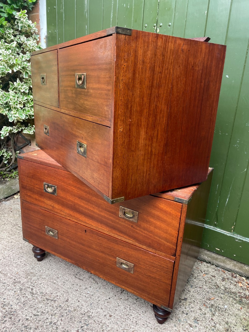 A mid-nineteenth century brass-bound teak campaign chest of drawers featuring two-part construction, recessed brass handles, corner straps, and turned feet. View XII
