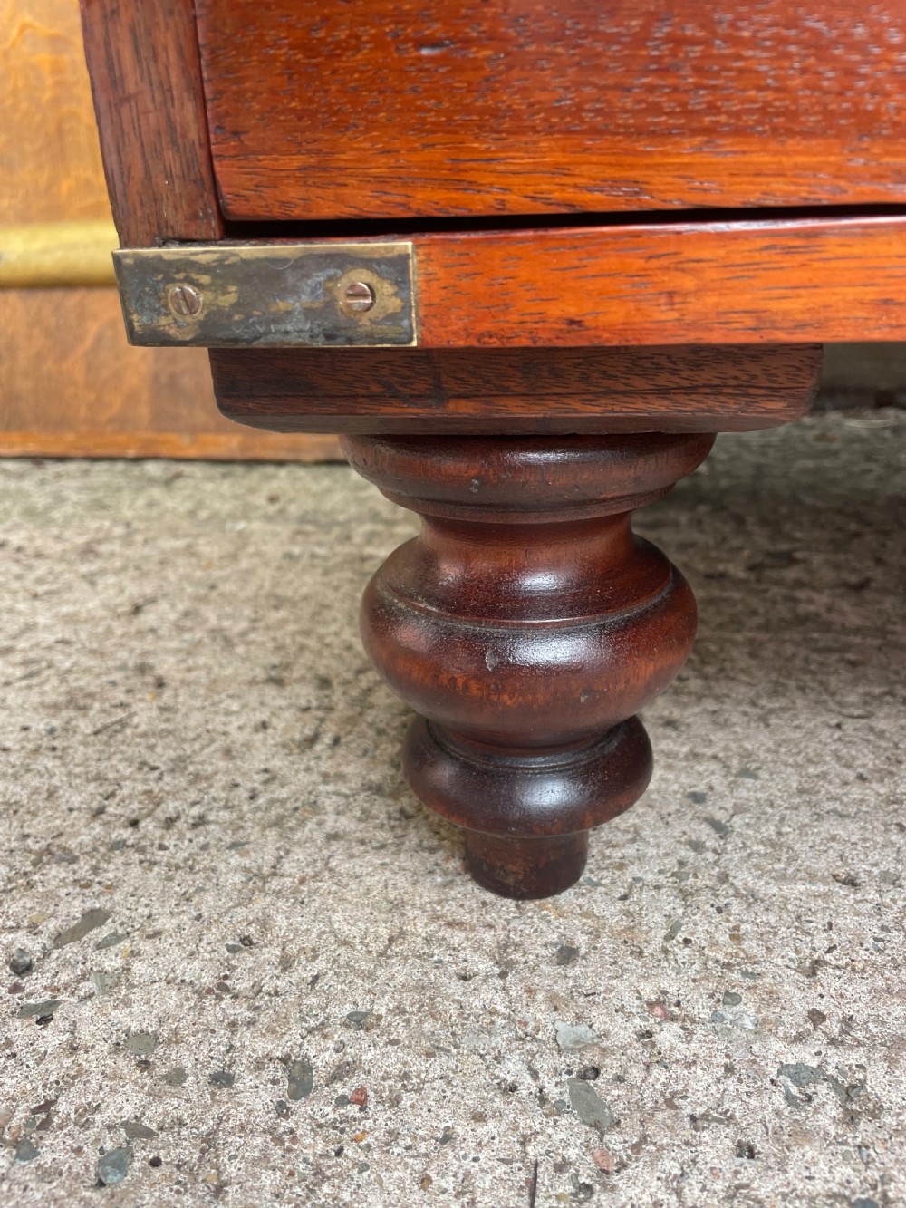 A mid-nineteenth century brass-bound teak campaign chest of drawers featuring two-part construction, recessed brass handles, corner straps, and turned feet. View XIII