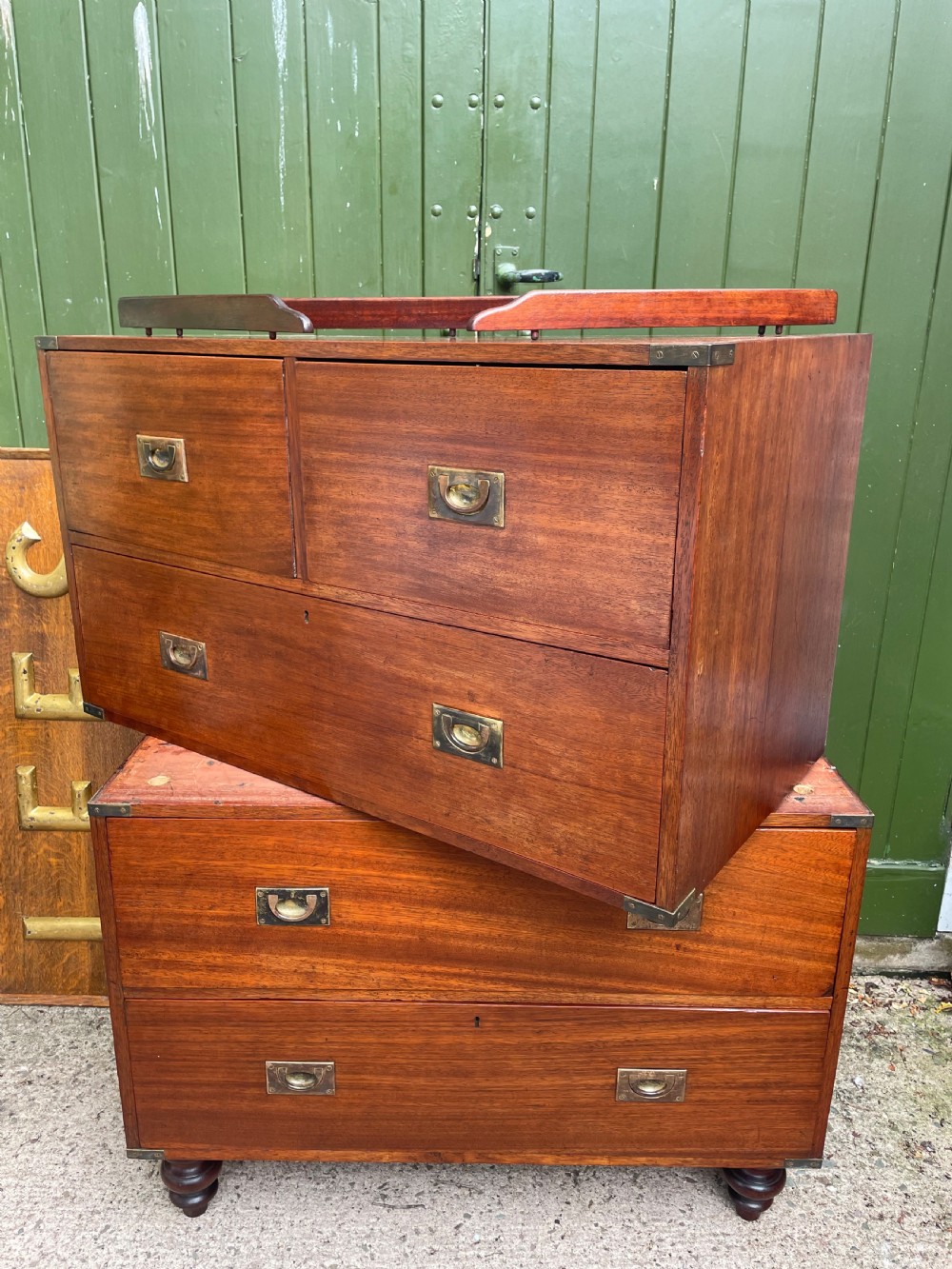 A mid-nineteenth century brass-bound teak campaign chest of drawers featuring two-part construction, recessed brass handles, corner straps, and turned feet. View XIV