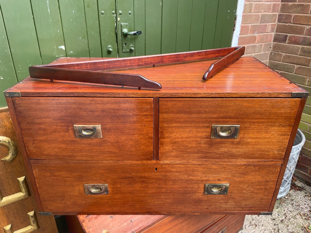 A mid-nineteenth century brass-bound teak campaign chest of drawers featuring two-part construction, recessed brass handles, corner straps, and turned feet. View XVI