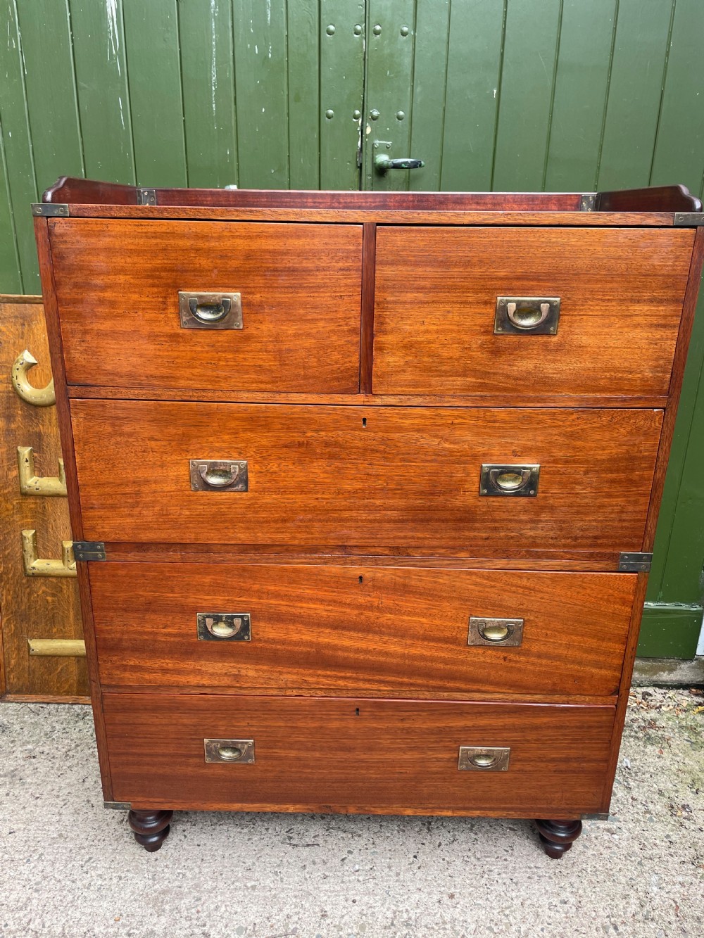 A mid-nineteenth century brass-bound teak campaign chest of drawers featuring two-part construction, recessed brass handles, corner straps, and turned feet. View XIX