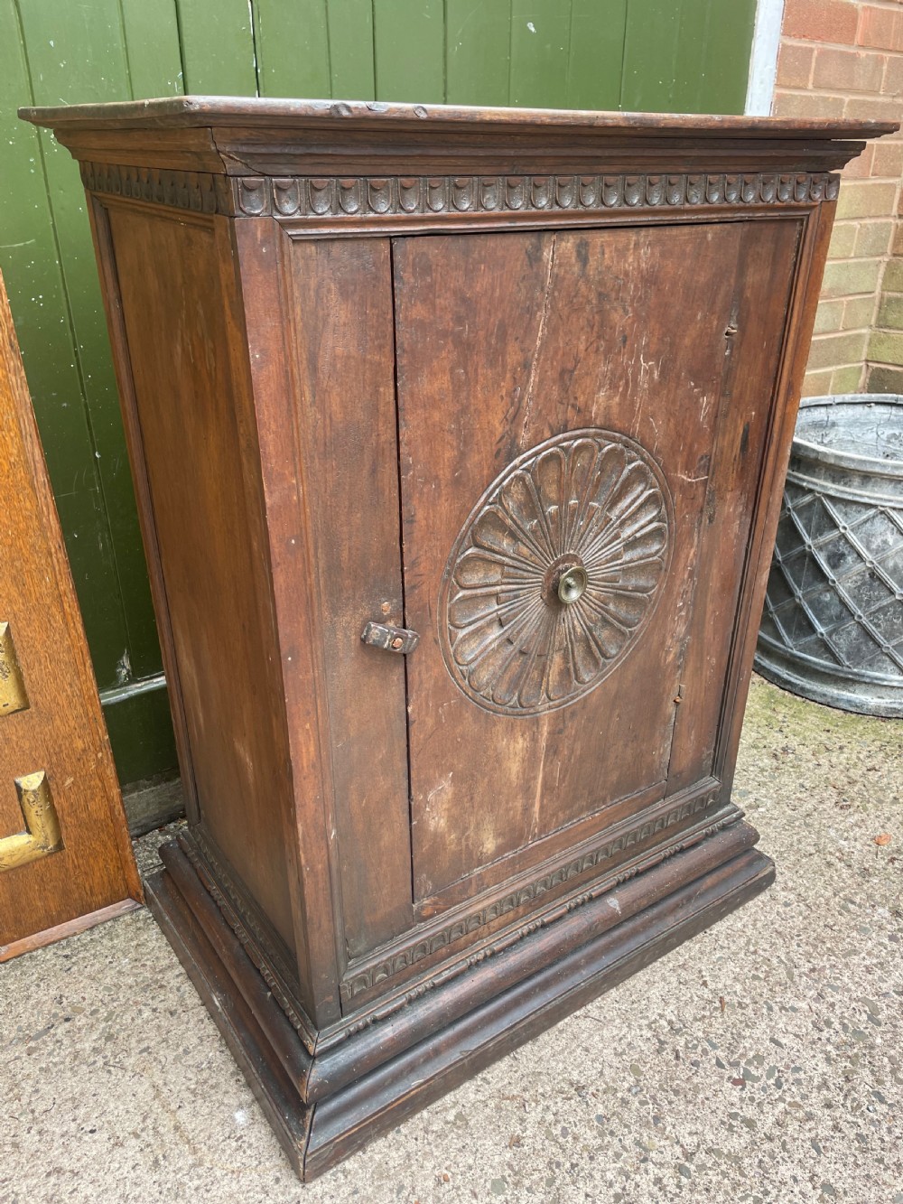 An early 18th-century Italian Tuscan walnut pedestal cupboard featuring a single cupboard door carved with a central circular rosette motif and framed by architectural moulding on a plinth base. View III